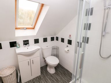 A bathroom with a toilet sink shower and a skylight window at Barn 2 Ystradgynlais