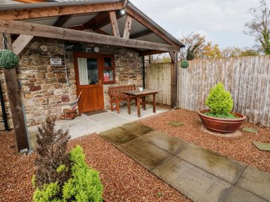 A stone cottage entrance with wooden door bench and table a stone pathway and potted plants at Barn 3 Cwm-twrch Isaf near Ystradgynlais