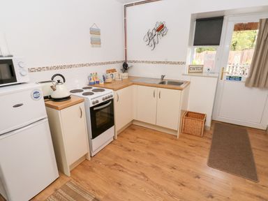 A kitchen with a refrigerator, microwave, stove, sink, and cabinets at Barn 3 Cwm-twrch Isaf near Ystradgynlais