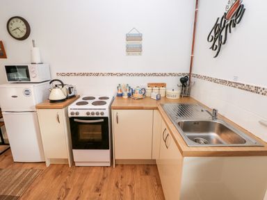A kitchen with a white stove oven a microwave on top of a refrigerator a kettle toaster set of ceramic containers and a sink at Barn 3 in Cwm-twrch Isaf near Ystradgynlais