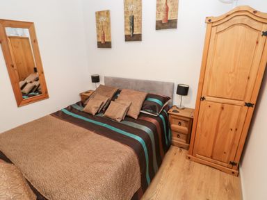 A bedroom with a bed pillows wooden bedside tables lamps wardrobe and a wall mirror at Barn 3 Cwm-twrch Isaf near Ystradgynlais
