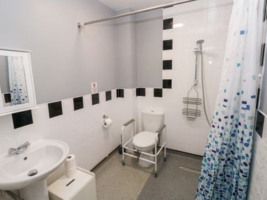 A bathroom with a sink toilet with support rails shower curtain and tiled walls at Barn 3 in Cwm-twrch Isaf near Ystradgynlais