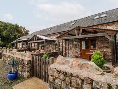 A stone building with wooden porch covers and small gardens behind stone walls at Barn 3 Cwm-twrch Isaf near Ystradgynlais