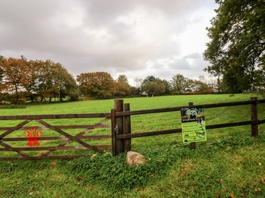 A wooden fence and gate in front of a green field with trees in the background at Barn 3 Cwm-twrch Isaf near Ystradgynlais