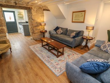A sitting room with two gray sofas a wooden coffee table and stone walls at The Old Post Office in Praze-An-Beeble