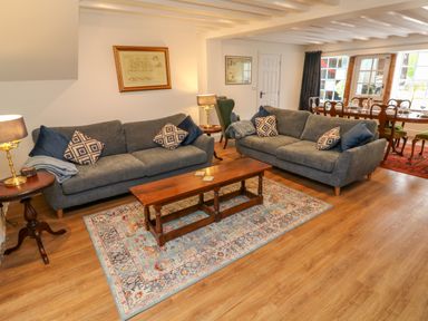 A living room with two gray sofas a wooden coffee table and a dining table in the background at The Old Post Office in Praze-An-Beeble