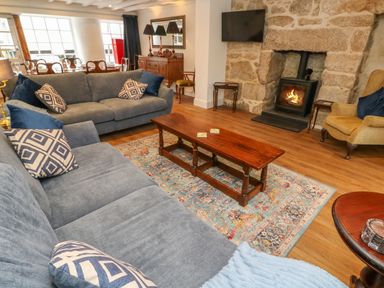 A living room with blue sofas a wooden coffee table a fireplace and wooden furniture at The Old Post Office in Praze-An-Beeble
