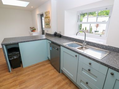 A kitchen with a double sink dishwasher and blue cabinets at The Old Post Office in Praze-An-Beeble