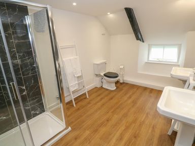 A bathroom with a shower enclosure toilet sinks and a window at The Old Post Office in Praze-An-Beeble