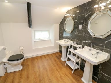 A bathroom with two sinks and mirrors a toilet and wooden floor at The Old Post Office in Praze-An-Beeble