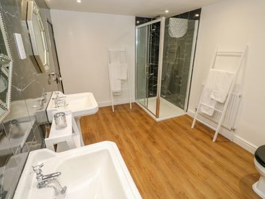 A bathroom with two sinks a shower cubicle and towel ladders at The Old Post Office in Praze-An-Beeble
