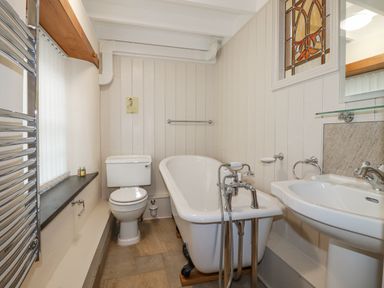 A bathroom with a clawfoot bathtub toilet sink and stained glass window at Mill Cottage in St Neot