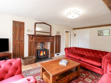 A living room with red sofas wooden coffee table fireplace and television at West House Farm in Leiston