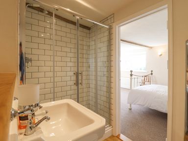A bathroom with a sink and a glass shower door leading to a bedroom with a bed at West House Farm in Leiston