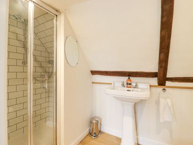 A bathroom with a shower cubicle a pedestal sink a round mirror and a towel ring at West House Farm Leiston
