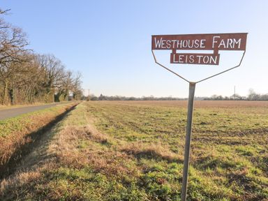A road running beside open fields with a sign reading Westhouse Farm Leiston