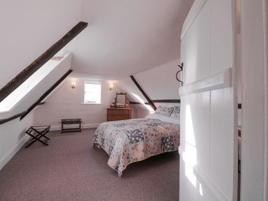 A bedroom with a bed a wooden dresser with mirror two wall lights and two luggage racks at West House Farm in Leiston
