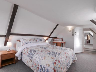 A bedroom with a bed a wooden bedside table and a small wooden desk at West House Farm Leiston