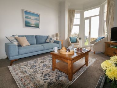 A living room with a blue sofa and a wooden coffee table with food on it at Blue Yonder in Weymouth