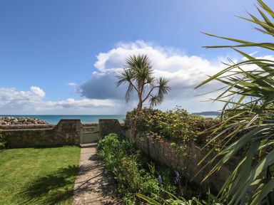 A garden with a stone path leading to a gate overlooking the sea at Blue Yonder in Weymouth