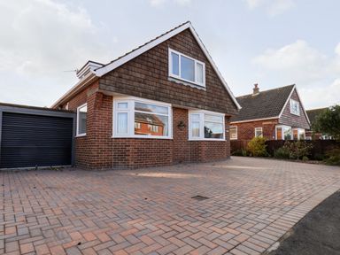 A brick house with a paved driveway and a garage at Meadowfields in Whitby
