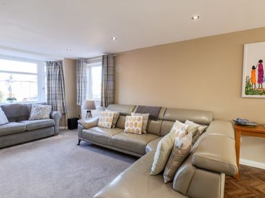 A living room with two sofas pillows a floor lamp curtains and a painting on the wall at Meadowfields in Whitby