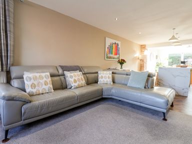 A living room with a grey leather sectional sofa and cushions at Meadowfields in Whitby