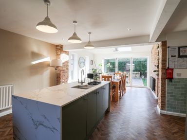 A kitchen with a marble island and a dining table near glass sliding doors at Meadowfields in Whitby