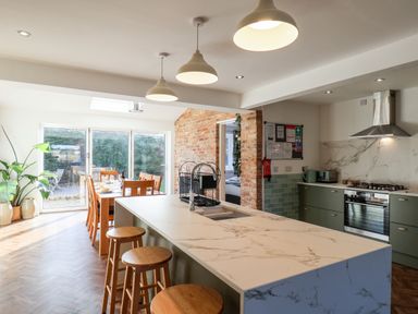 A kitchen with marble countertop island stools dining table and chairs and glass doors at Meadowfields in Whitby