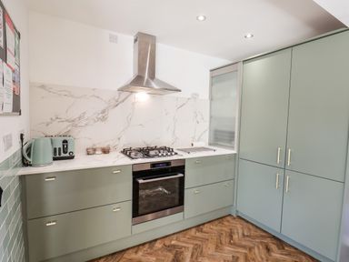 A kitchen with green cabinets a stainless steel oven a gas stove a toaster and kettle on the counter at Meadowfields in Whitby