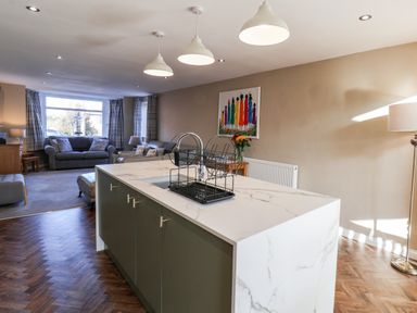 An open living area with a kitchen island and a sitting area with sofas and windows at Meadowfields in Whitby