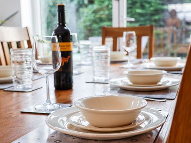 A dining table set with plates bowls wine glasses and a bottle of wine at Meadowfields in Whitby