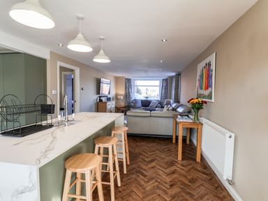 An open plan kitchen and living room with bar stools and a sofa at Meadowfields in Whitby