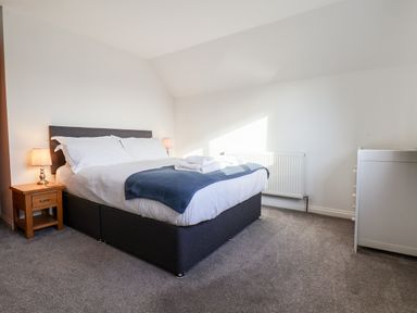 A bedroom with a double bed bedside tables with lamps a radiator and a chest of drawers at Meadowfields in Whitby