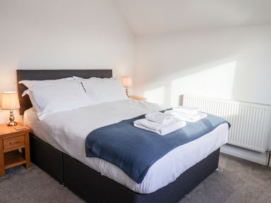 A bedroom with a double bed two bedside tables with lamps and folded towels on the bed at Meadowfields in Whitby