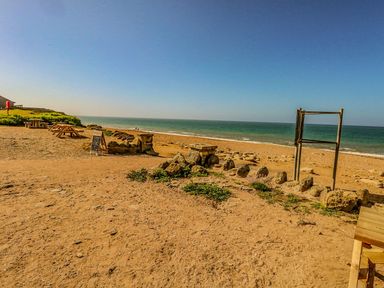 A sandy beach with picnic tables and stone barriers by the sea at Alice's Cottage in Burton Bradstock