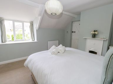 A bedroom with a bed and rolled towels on it and a window at Alice's Cottage in Burton Bradstock