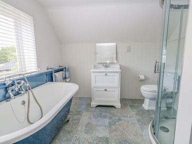 A bathroom with a bathtub sink toilet and shower at Alices Cottage in Burton Bradstock