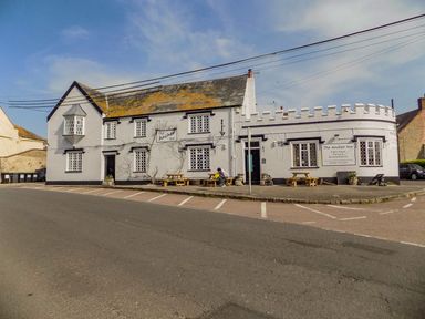 A pub building with outdoor benches and parking spaces at Alice's Cottage in Burton Bradstock