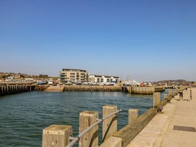 A harbor with boats docked and buildings in the background under a clear sky at Alices Cottage in Burton Bradstock