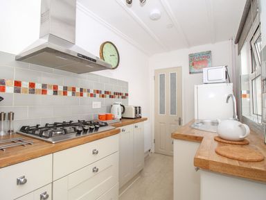 A kitchen with a stove microwave fridge kettle and teapot at Little Gull Cottage Weymouth
