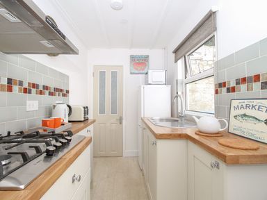 A kitchen with wooden countertops a gas stove a toaster a kettle a microwave and a sink at Little Gull Cottage in Weymouth