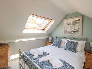 A bedroom with a double bed two wooden nightstands and a skylight window at Little Gull Cottage in Weymouth