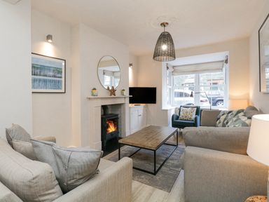 A living room with sofas a coffee table a fireplace and a window at Forty Five in Keswick