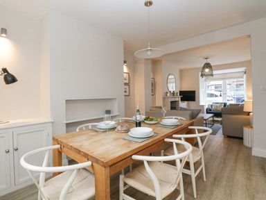 A dining area with a wooden table set for four and a living room with sofas and a TV at Forty Five in Keswick