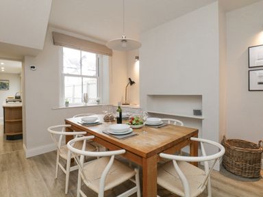 A dining room with a wooden table set for four and a window with a beige blind at Forty Five in Keswick