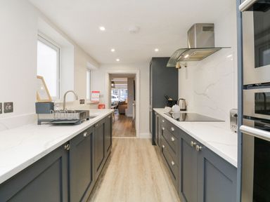 A galley kitchen with dark blue cabinets white countertops and stainless steel appliances at Forty Five in Keswick