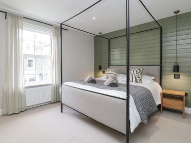 A bedroom with a four-poster bed pillows curtains and bedside table at Forty Five in Keswick