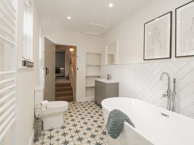 A bathroom with a bathtub toilet vanity shelves and wall art at Forty Five in Keswick