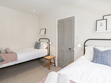 A bedroom with two single beds a wooden stool and framed pictures on shelves at Forty Five in Keswick